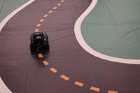 Photo of a DeepRacer autonomous vehicle on a vinyl racetrack.